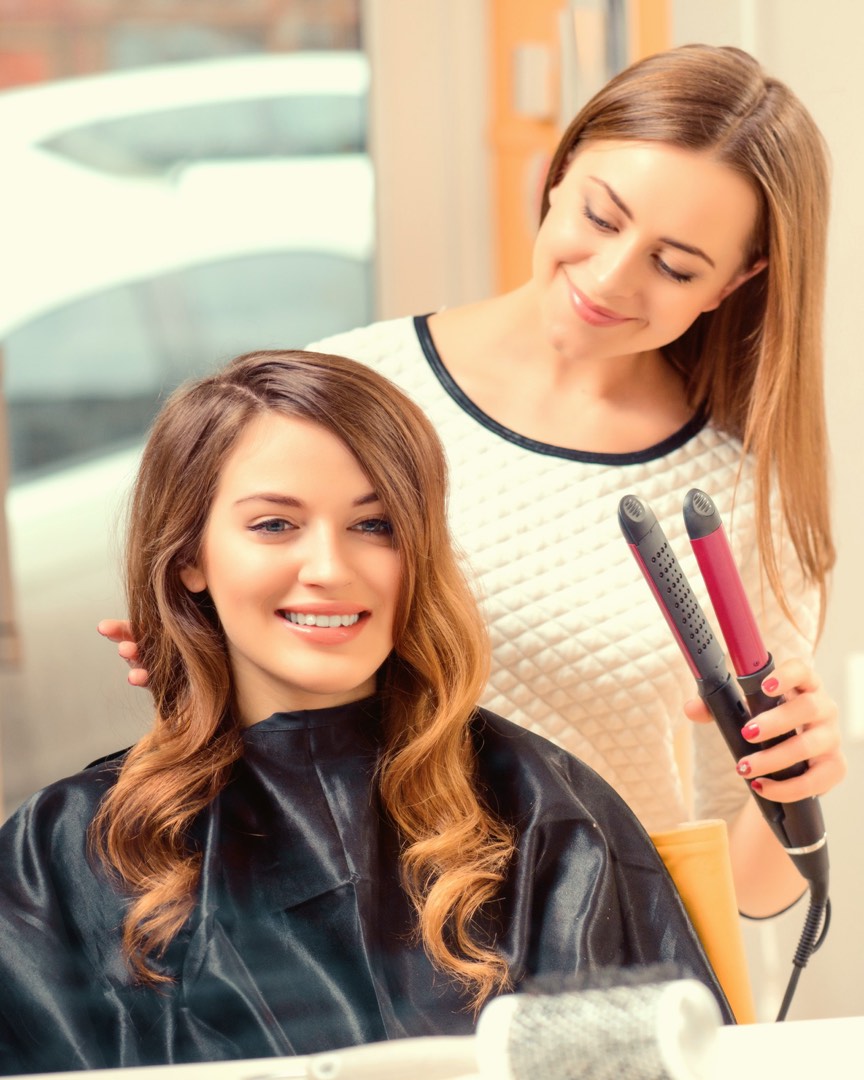 A hairstylist finishing a client's hair with a flat iron